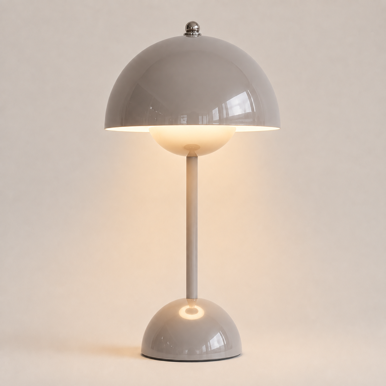 Gray table lamp with a rounded dome shade, slim stem, circular base, and warm downward glow.