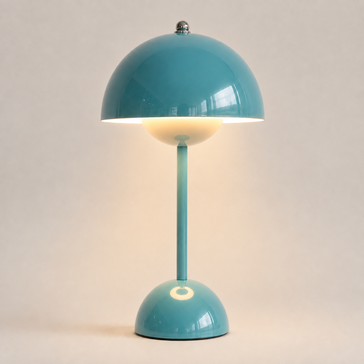 Teal table lamp with a rounded dome shade, slim stem, circular base, and warm downward glow.