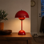 Red table lamp casting warm light on a wooden console beside a bowl and leafy plant.