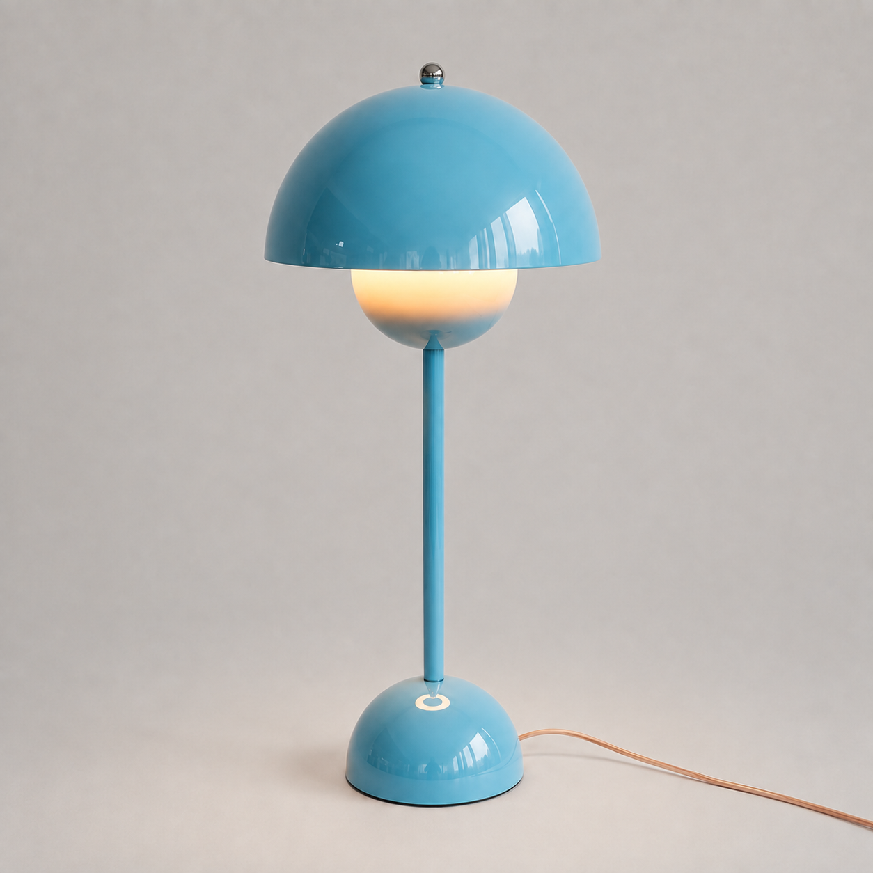 Blue table lamp with a rounded dome shade, slim stem, circular base, power cord, and warm downward glow.