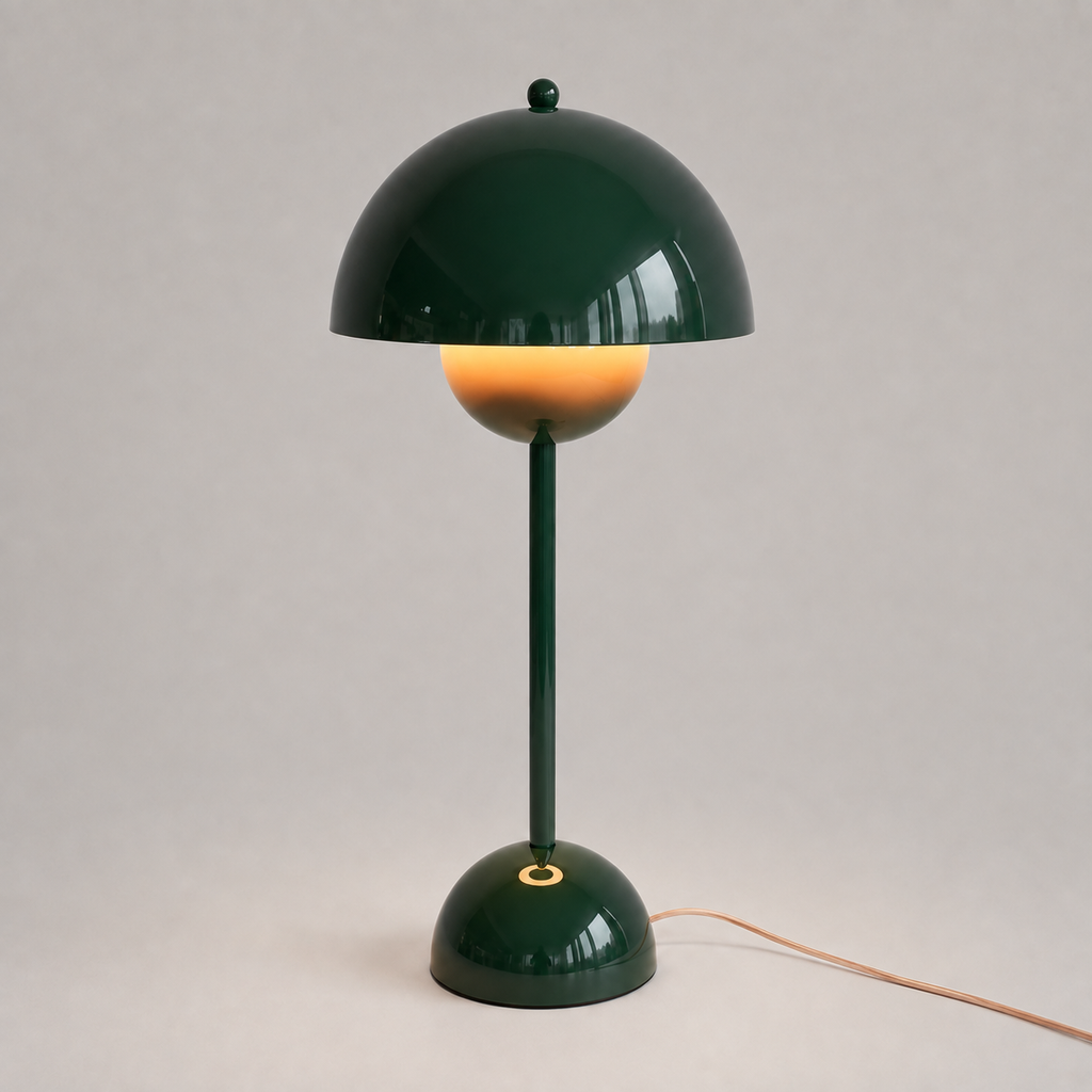 Green table lamp with a rounded dome shade, slim stem, circular base, power cord, and warm downward glow.