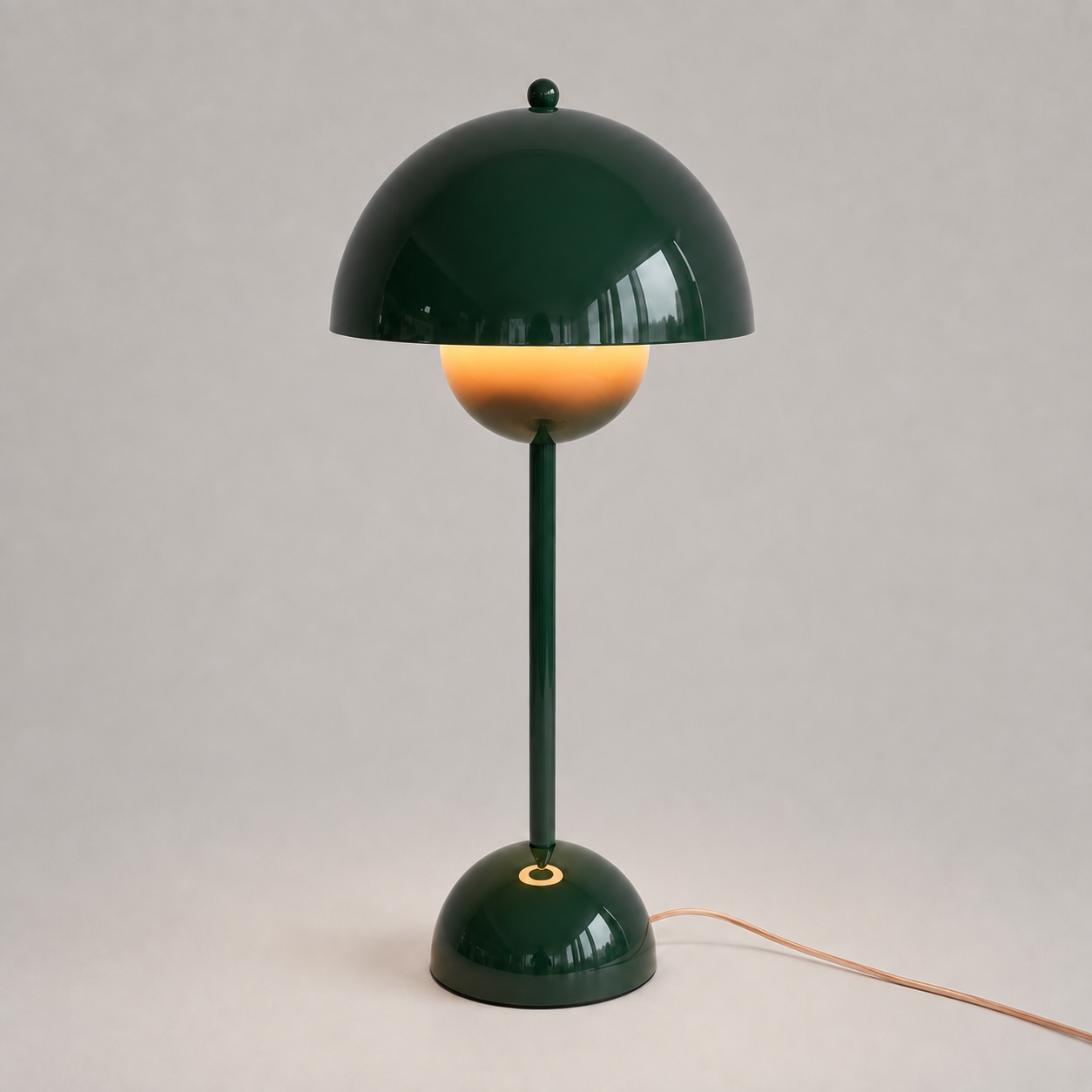 Green table lamp with a rounded dome shade, slim stem, circular base, power cord, and warm downward glow.