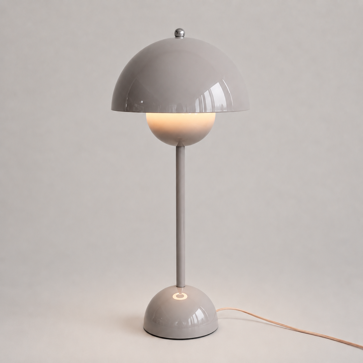 Gray table lamp with a rounded dome shade, slim stem, circular base, power cord, and warm downward glow.