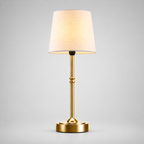 Gold cordless table lamp with a tapered white shade centered on a plain background.