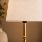 Close up of the table lamp base and slender gold colored stem.