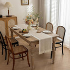 Beige table runner with woven zigzags and fringe on a dining table.