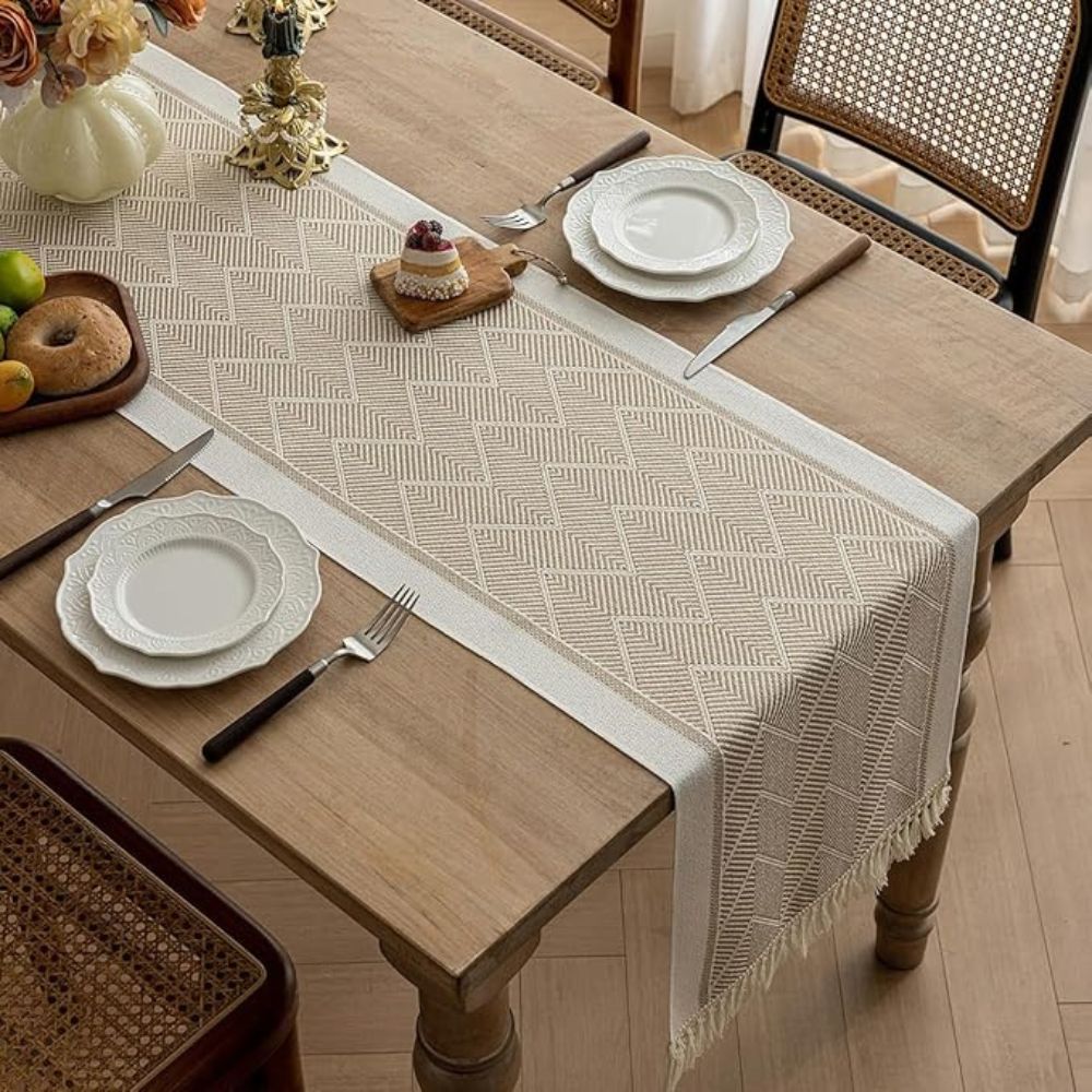 Beige table runner arranged beneath white plates on a dining table.