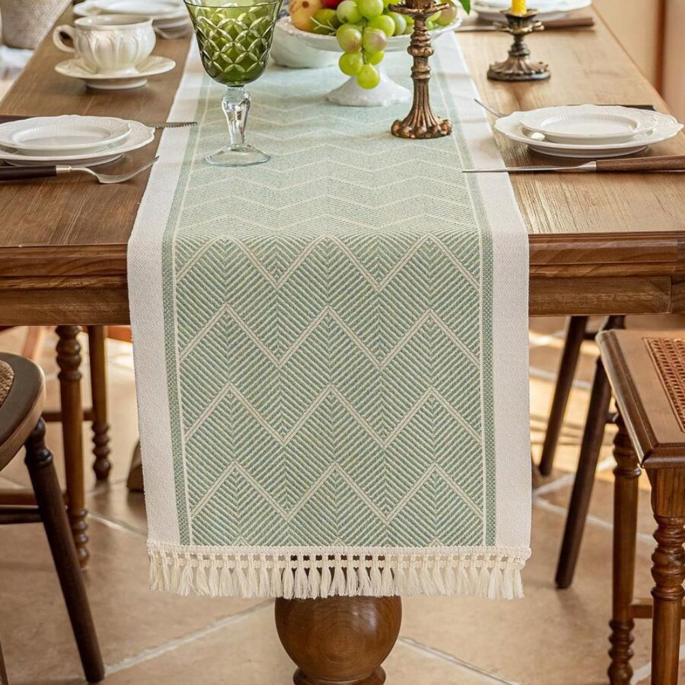 Green table runner running between place settings on a wood table.