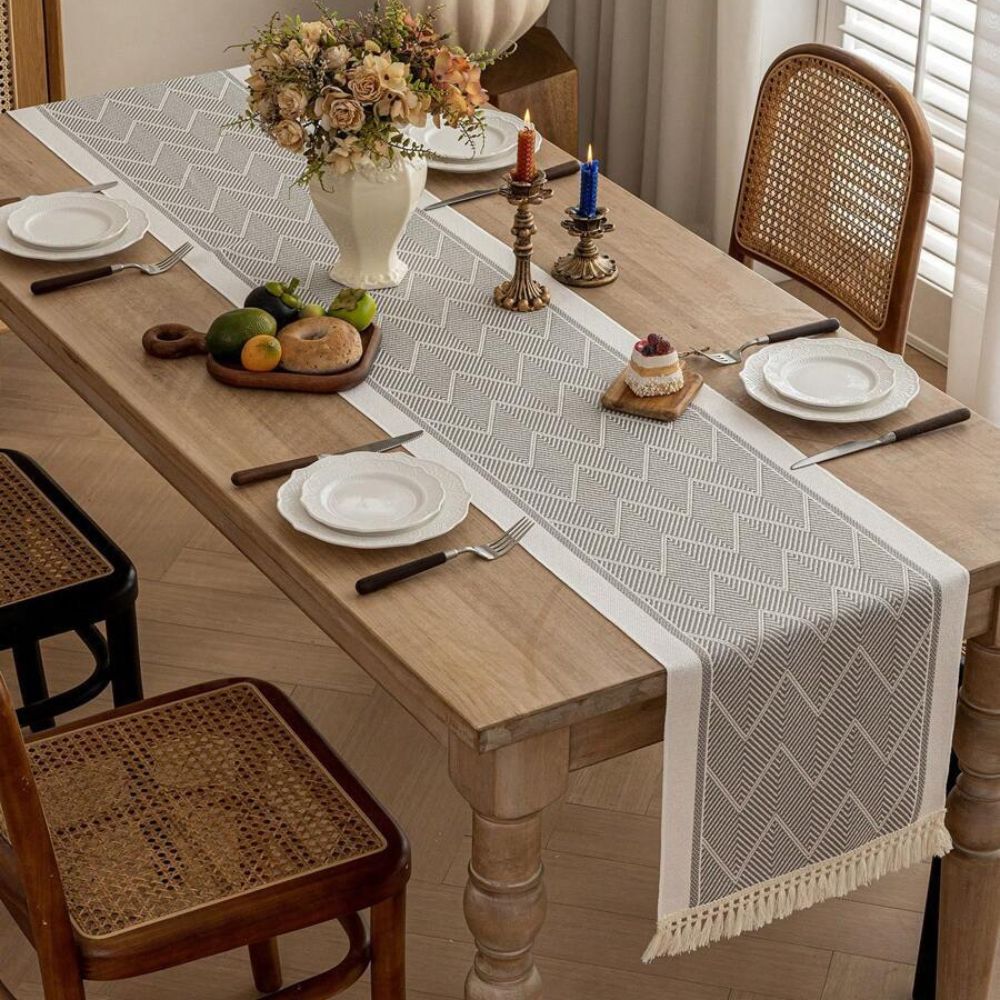 Gray table runner styled with white plates and flowers on a dining table.