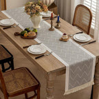 Gray table runner styled with white plates and flowers on a dining table.