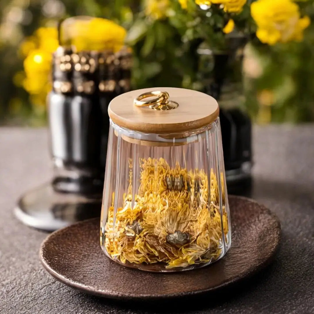 Conical ribbed glass tea storage jar with wooden lid and gold toned ring handle