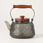 Patterned smoky gray glass teapot with wooden carry grip
