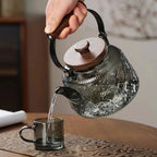 Patterned smoky glass teapot pouring into a cup