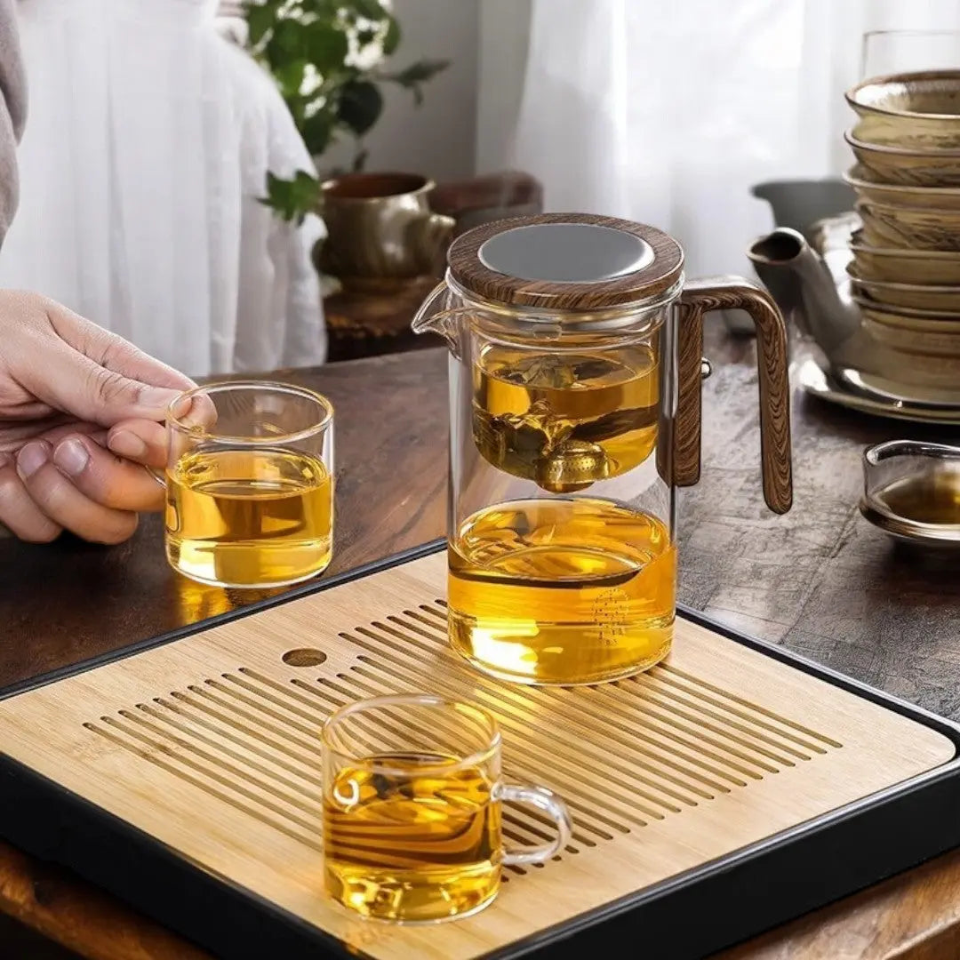 Glass teapot standing on a tea tray while tea is served