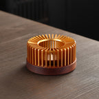 Slatted gold tone metal teapot warmer on a round brown base.