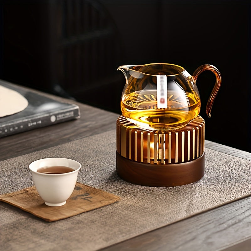 Glass teapot resting on a gold tone candle powered warmer.