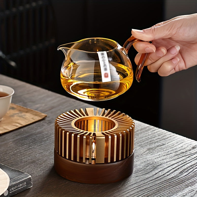 Hand lifting a glass teapot from a gold tone warmer.
