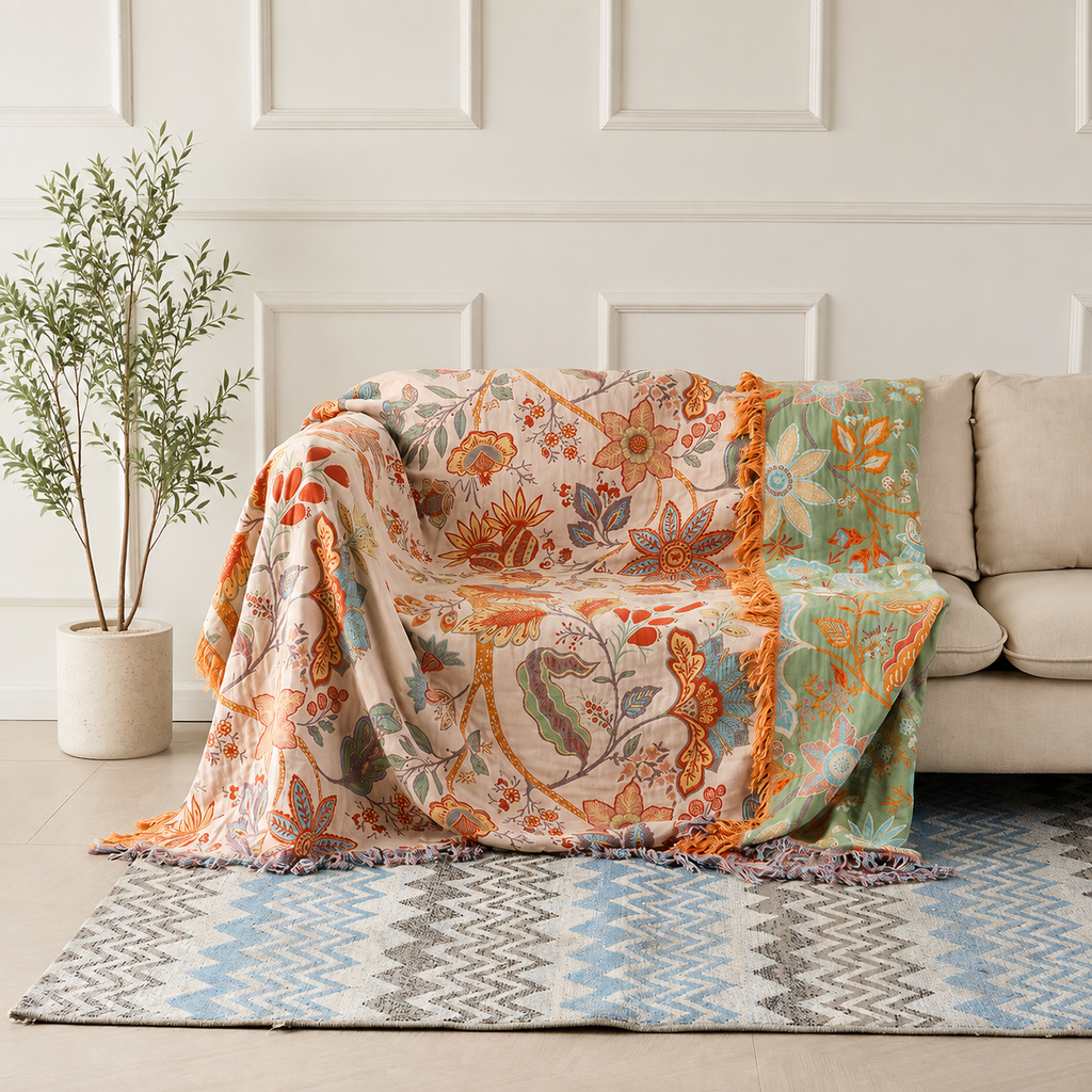 Boho floral throw blanket draped over a cream sofa with orange tassel fringe