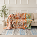 Boho floral throw blanket draped over a cream sofa with orange tassel fringe