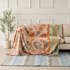 Boho floral throw blanket draped over a cream sofa with orange tassel fringe