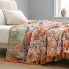 Boho floral throw blanket folded over a bed edge with orange tassels visible