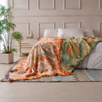 Boho floral throw blanket layered across a neutral bed with teal and orange pattern