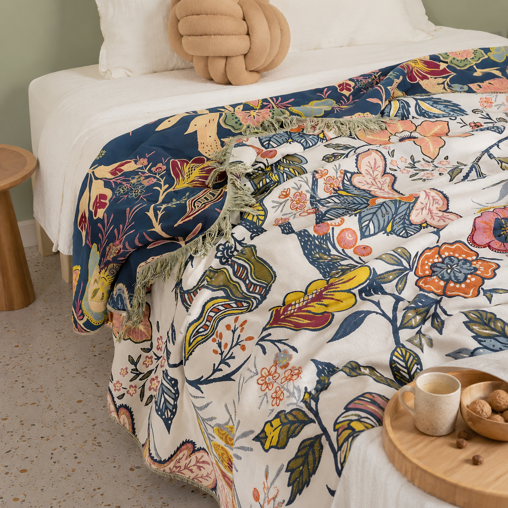 Artistic floral throw blanket spread across a bed with contrasting botanical panels