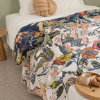 Artistic floral throw blanket spread across a bed with contrasting botanical panels