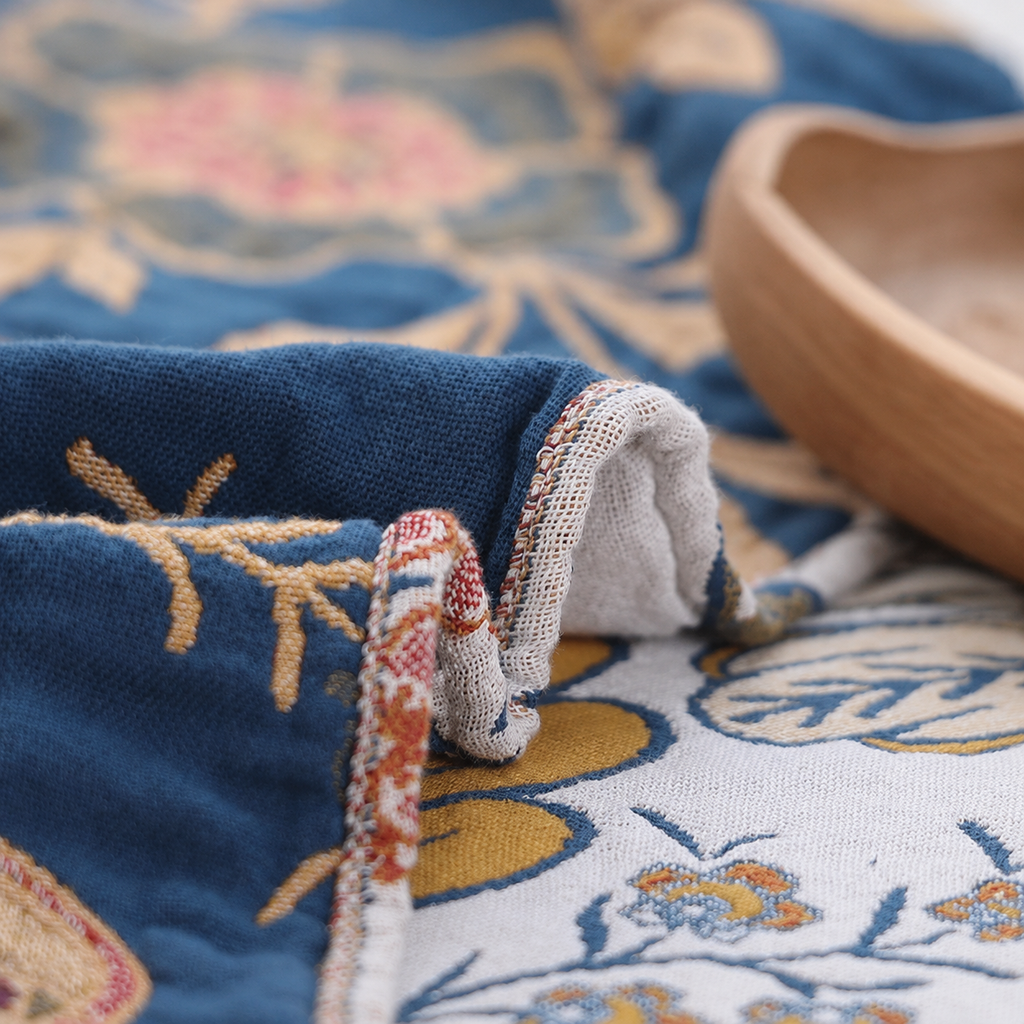 Artistic floral throw blanket folded close up showing blue border and soft reverse