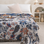 Artistic floral throw blanket fully spread across a bright neutral bed