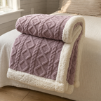 Sherpa fleece throw blanket in purple rolled and draped over a bed edge