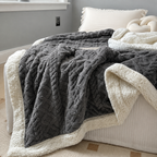 Sherpa fleece throw blanket in charcoal draped across a neatly made bed