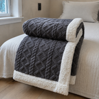 Sherpa fleece throw blanket in gray rolled and draped over a bed edge