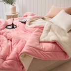 pink sherpa throw blanket spread across a white bed