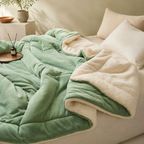 light green sherpa throw blanket spread across a cream bed