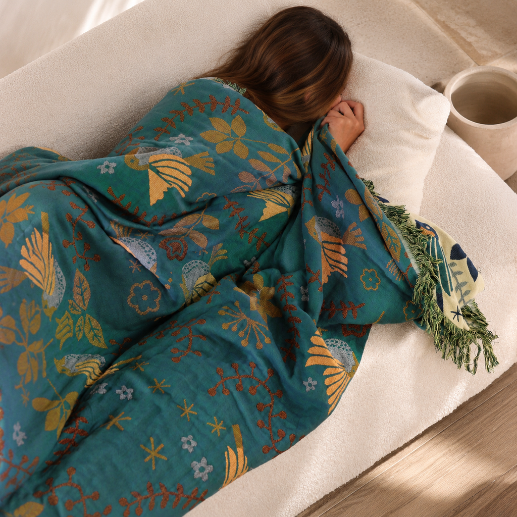 reversible bird throw blanket wrapped around a resting person with face hidden