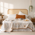 cream mandala throw blanket draped across a bright woven-headboard bed