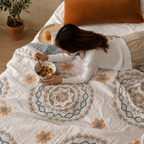 cream mandala throw blanket on a bed beneath a seated person