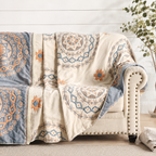 woven mandala throw blanket draped over a light upholstered armchair