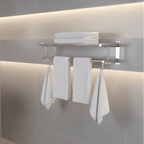 Towel rack in matte silver mounted on a tiled wall with folded and hanging white towels.