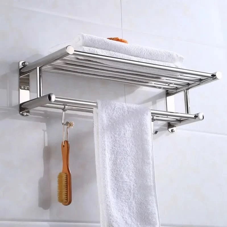 Towel rack mounted on pale tile with a hanging white towel and wooden brush.