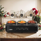 Black triple slow cooker with three raised glass lids on a holiday table