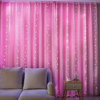 Fairy curtain lights glow soft pink behind a sofa.