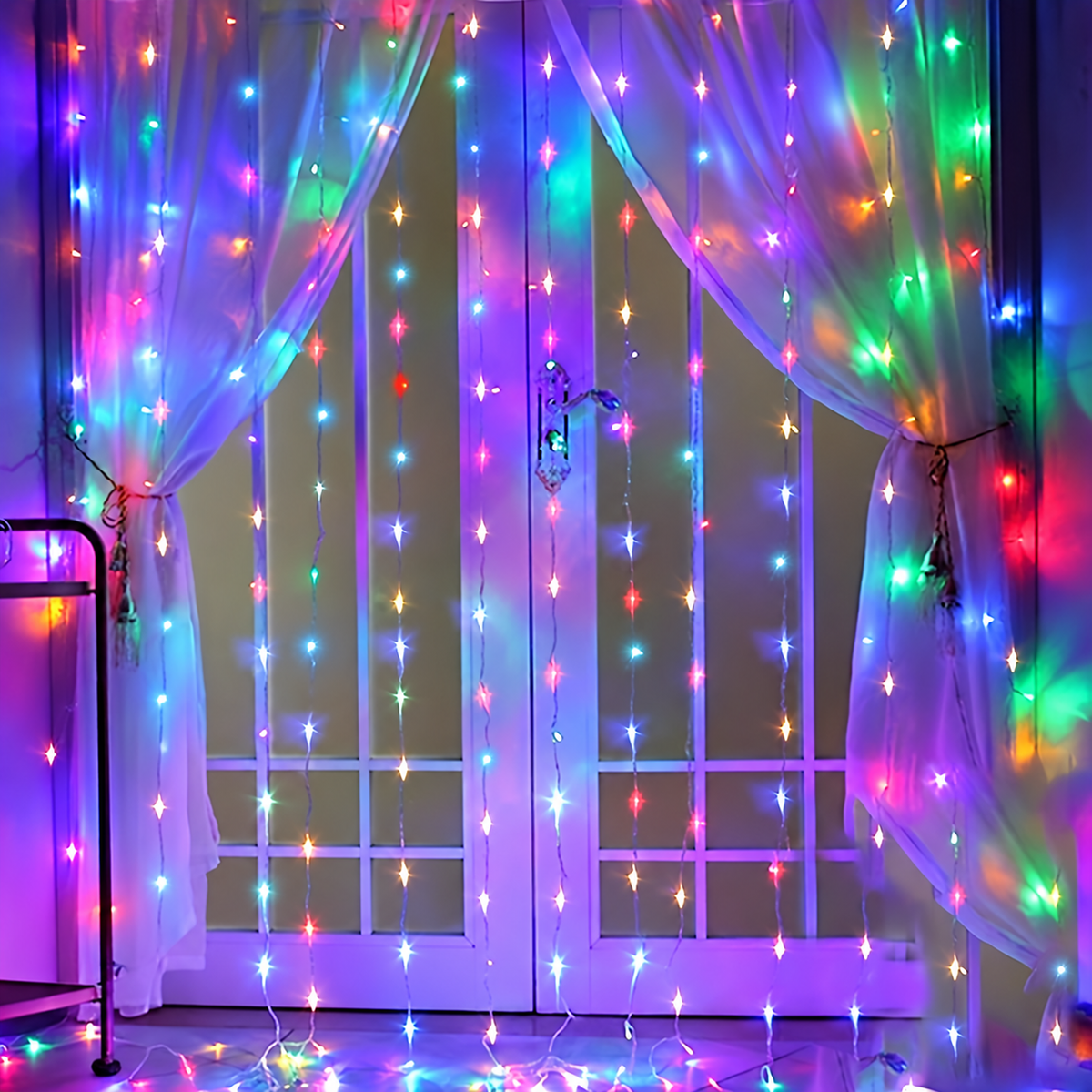 Multicolor curtain fairy lights glowing across sheer window curtains.