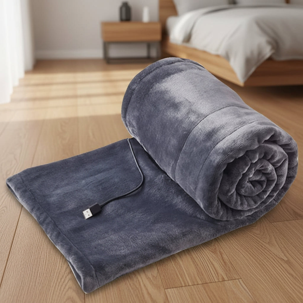 USB heated blanket in gray rolled on a wooden floor with the power cable visible.