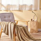 USB heated blanket in beige draped across a chair in a bright room.
