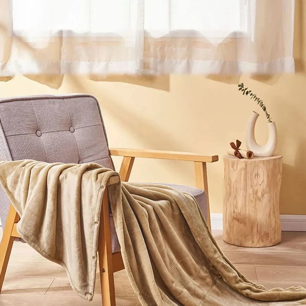 USB heated blanket in beige draped across a chair in a bright room.