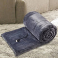 USB heated blanket in gray rolled beside a sofa with the USB cable visible.