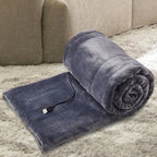 USB heated blanket in gray rolled beside a sofa with the USB cable visible.