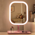 Pink vanity makeup mirror illuminated with warm light on a dressing table.